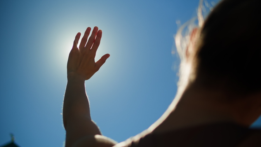Woman closing sun by hand, blue sky, covering sunlight with arm. Young person looking at bright light. Royalty-Free Stock Footage #1096179601