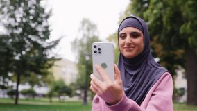 Arab woman having online video call on smartphone, social media influencer