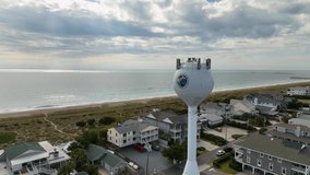 Aerial video of flight over hotels at beach and water tower.