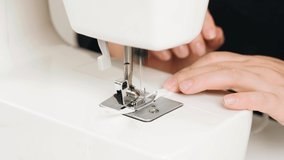 Work at home. Small business. A female seamstress sews white fabric items on a sewing machine. Close-up.
