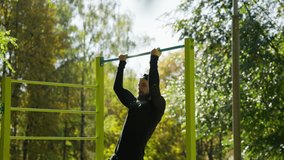 Sportsman doing pull-ups on the sports field in the park - Powered by Shutterstock - Get 15% off with code: PIKWIZARD15