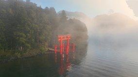 Japanese culture, Hakone shrine with famous torii on the lake on magical foggy morning, tourism in Japan, aerial view of beautiful Japanese lake Ashino. High quality 4k footage