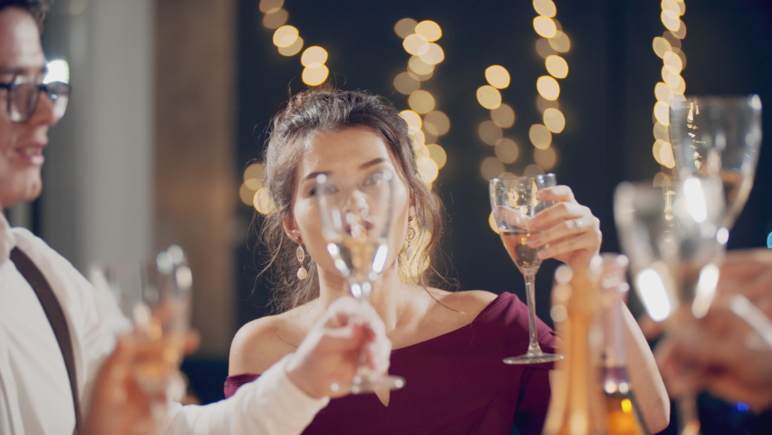 Friends cheers at the festive table at night Christmas at home. Christmas party, new year holiday and vacation. Young people celebrate together, enjoying themselves, drink champagne, talking and laugh Royalty-Free Stock Footage #1096187121