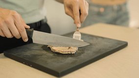 4K video of a a man's hands cutting cooked tuna on a board