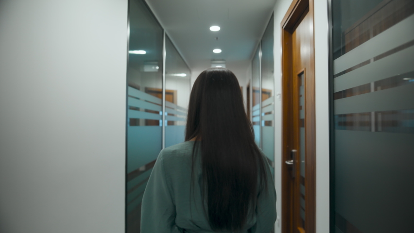 Back view employee walking on meeting through office corridor. Closeup professional woman thinking about project in business center hallway. Serious manager going on dinner in open space alone  Royalty-Free Stock Footage #1096190545