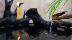 Flowing water, bamboo gutter pipes, candles on black stumps, spa treatment concept.