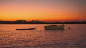 Real time 4k movie, sunset in the bay, silhouette of a boat in the background of the bay, fish jumping out of the water, vacation in the mediterranean