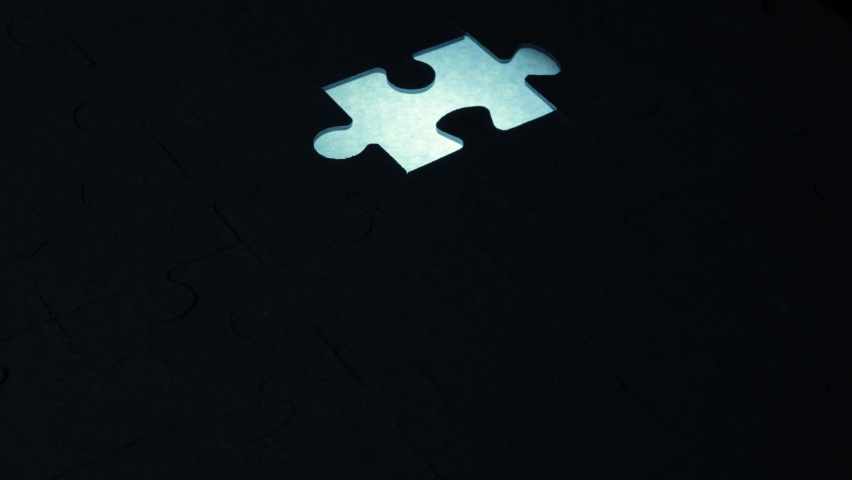 A creative completes the black or white light puzzle putting the last missing piece. Concept: cooperation, teamwork, creativity, and access solution