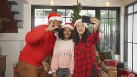 An African American black family, woman, father, mother and kid girl taking a selfie by phone in party on Merry Christmas Eve Xmas on holiday. Celebration at home. People lifestyle. - Powered by Shutterstock - Get 15% off with code: PIKWIZARD15