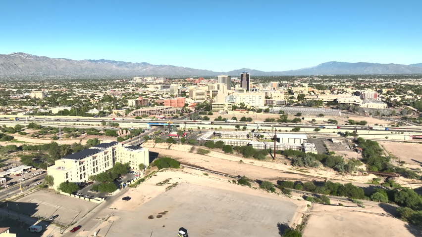 Drone shot of Tuscon Arizona, with traffic on the highway, with mountains in the distance on a sunny day, slowly rotating aerial shot.
