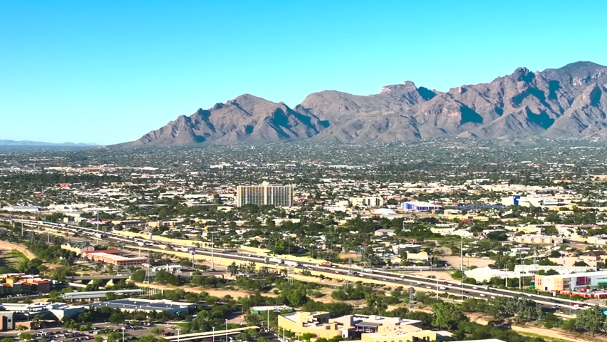 Drone shot of Tuscon Arizona, with traffic on the highway, with mountains in the distance on a sunny day.