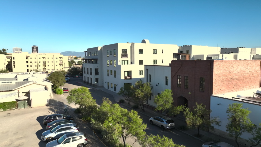 Drone shot of businesses, homes, townhomes, apartments in Tuscon Arizona into the sun, slowly rotating low angle aerial shot.