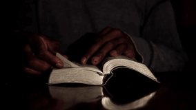 praying to god with hands together with bible and cross Caribbean man praying with black background stock video