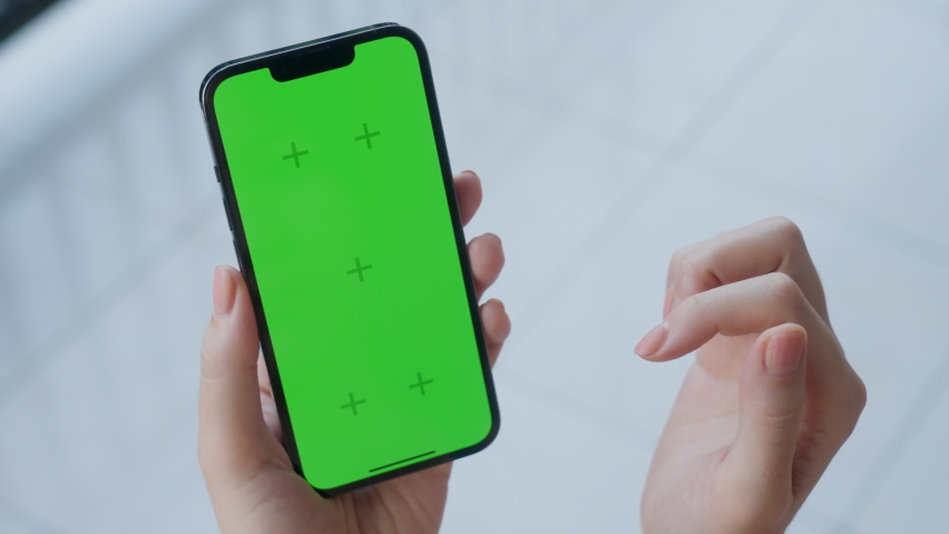 Point of view of a woman holding mobile phone and touching the touch screen with her finger and opening application. Use green screen for copy space closeup. Chroma key mock-up on smartphone in hand.  Royalty-Free Stock Footage #1096211009
