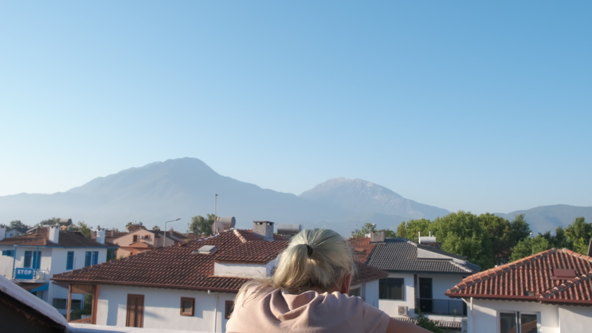 Morning greeting on the balcony. The girl on the balcony greets the morning.
