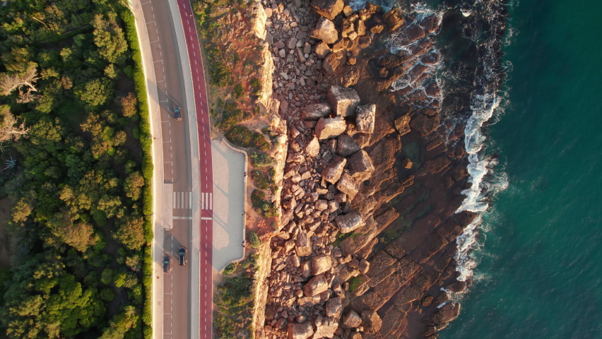 Aerial drone footage of the rocky coast by the sea in Cascais town at sunset, Lisbon, Portugal. Top down view of the coastal road near the natural landmark Boca do Inferno in Cascais city.  | Shutterstock HD Video #1096229895