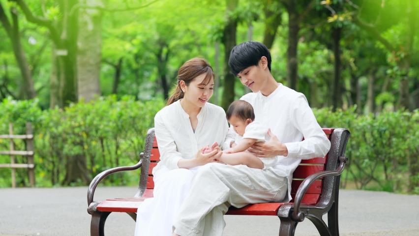 Asian couple and baby relaxing in green park. Child rearing. Newborn. Royalty-Free Stock Footage #1096234645