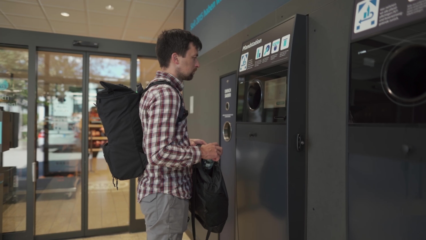 Male returns plastic bottles, reusable containers to reverse vending machine in Munich, Germany supermarket. Man using bottle deposit point. Automatic bottle recycling machine for collection plastic. 