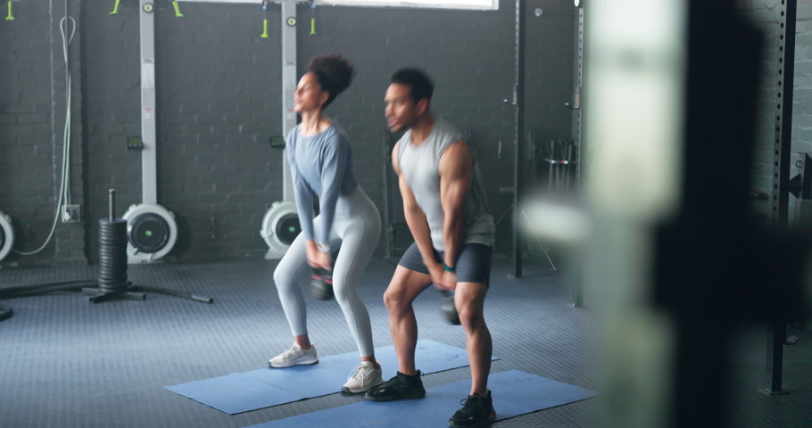 Exercise, black woman and man with kettlebell, fitness and workout for health, wellness and in gym. Healthy couple, gym equipment and doing training with stretching, routine and focus in sportswear. | Shutterstock HD Video #1096238125