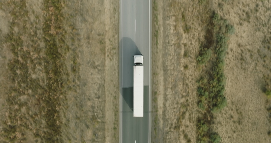 One Semi Truck with white trailer and cab driving, traveling alone on straight empty flat road through steppe, highway perspective follow vehicle drone view. Freeway trucks traffic Royalty-Free Stock Footage #1096242415