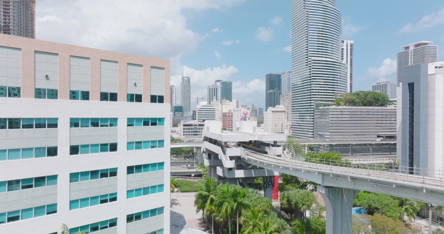 Fly over Metromover track leading on columns above park. Modern passenger transport vehicle in metropolis. Miami, USA