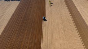 Aerial view of tractor with mounted plow works the agricultural field