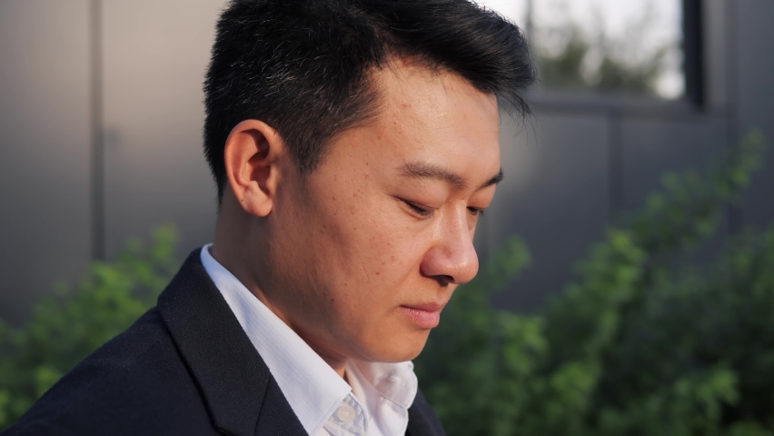 Closeup Portrait Face of Attractive Adult Chinese Man looking up Enjoying the City. Businessman, Entrepreneur, freelancer standing outdoors looking at Architecture of Town. Dreaming Business Man.