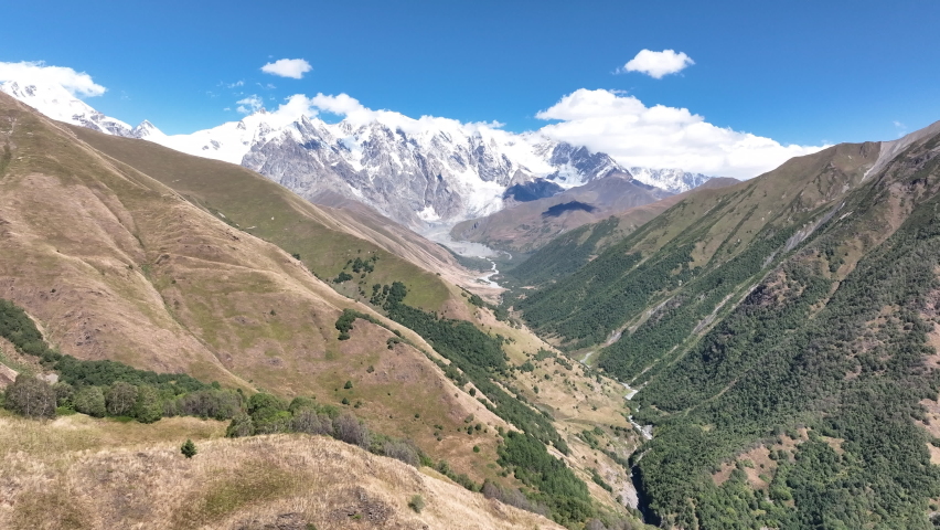 Flight over the mountains with bachground of Mount Shkhara in the region of Svaneti, Georgia