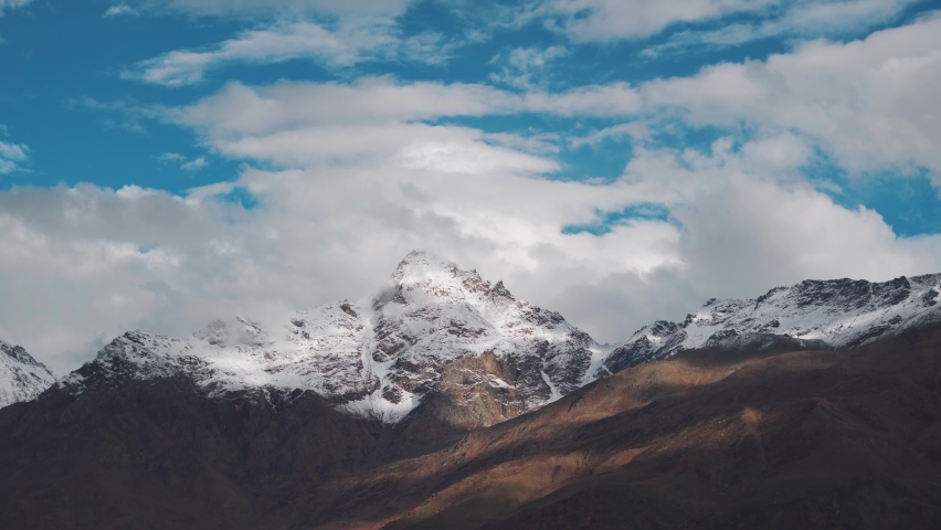 4K shot of clouds moving above the snow covered mountain peaks as seen from Keylong in Lahaul Spiti district in Himachal Pradesh, India. Clouds above the snowy Himalayan mountain peaks in Himachal.  | Shutterstock HD Video #1096248807