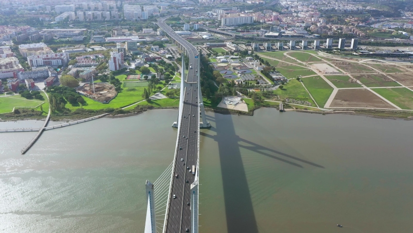 Cinematic aerial view of Vasco da Gama Bridge. Is a cable-stayed bridge flanked by viaducts that spans the Tagus River in Lisbon. It is the second longest bridge in Europe. Drone backward and tilt up.