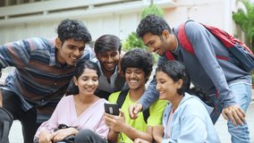 group of happy smiling stundets busy wathcing mobile phone during break time - concept of social media sharing, internet and entertainment