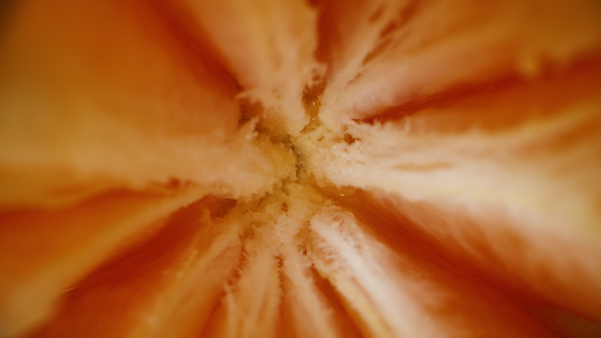 The top view. super macro. The tangerine divided into slices rotates on a black background. Dolly slider