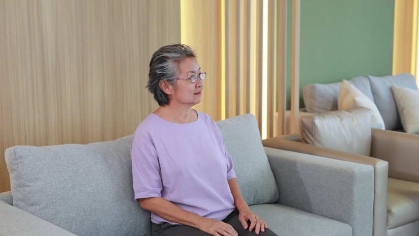 Elderly asian woman tries to get up from the sofa with acute back pain, Elderly health problems Royalty-Free Stock Footage #1096254109
