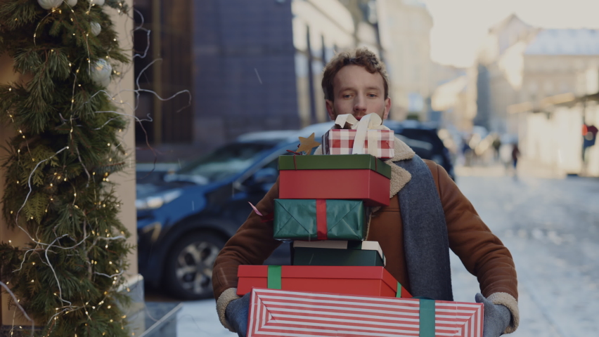 Caucasian man rushly is running home from the gift shop with many boxes and gifts fall from his hands, man feeling sad. People and christmas holidays concept