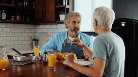 Smiling senior couple talking while eating breakfast at home. - Powered by Shutterstock - Get 15% off with code: PIKWIZARD15