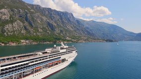 Aerial video. A big cruize ship is moving through the Boka Kotor Bay. Summer in Montenegro. Slowmotion shot