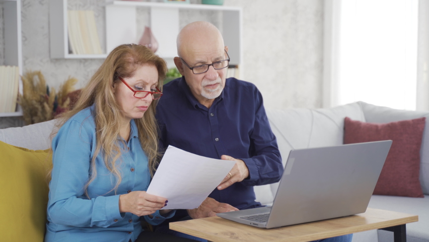 The old couple is saddened by the bad news.
The elderly couple receives sad news in a paperwork they are looking at.
