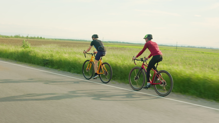 Active caucasian men in sportswear and helmet spending time for outdoor cycling with green summer field on background. Concept of people and workout.