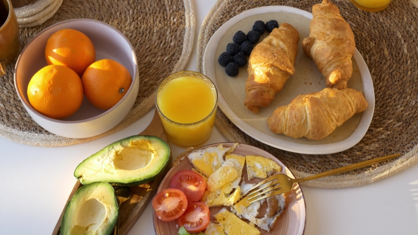 Top view of a balanced breakfast, full breakfast with croissants and scrambled eggs with vegetables, fruits, everything you need keep your body good shape. Proper nutrition key to success and health.