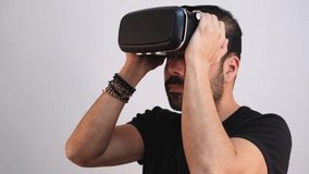 Young man using VR glasses headset gesturing excited, portrait on light background. Virtual reality, future technology, education video gaming.