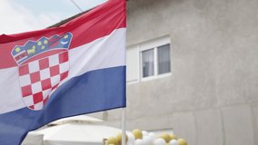 A closeup shot of the flag of Croatia blowing in the wind with balloons in the background
