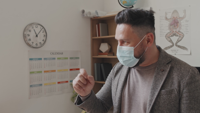 Waist-up of male Caucasian professor wearing face mask, giving anatomy lecture to invisible students in morning - Powered by Shutterstock - Get 15% off with code: PIKWIZARD15