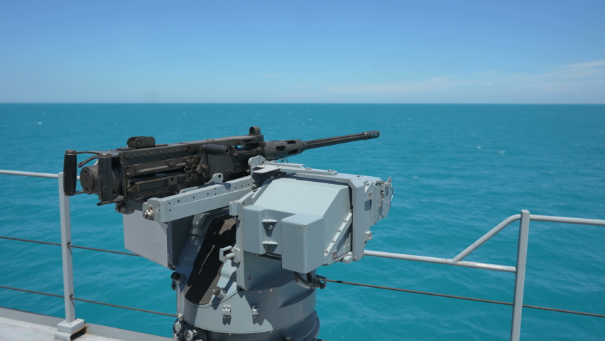 Color image of an automated machine gun on the deck of a military ship, at sea.