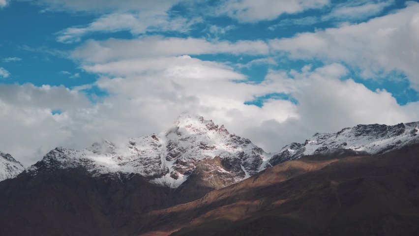 4K shot of clouds moving above the snow covered mountain peaks as seen from Keylong in Lahaul Spiti district in Himachal Pradesh, India. Clouds above the snowy Himalayan mountain peaks in Himachal.  | Shutterstock HD Video #1096296685