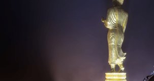 4K DCI Time lapse zoom out video at night to day with heavy fog of Golden lord buddha statue standing on hill, Phra Buddha Maha Udomonkol Nantaburee Sri Nan, at Wat Phra That Khao Noi, Nan, Thailand