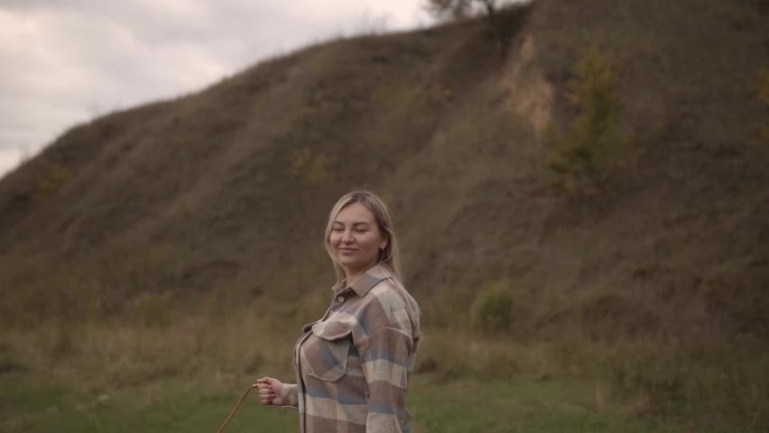 Attractive woman walking in the park turns around with flying hair and looks at the camera. Happy relaxed lady walks in the autumn park, enjoying.