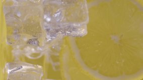 Water drips flowing from a sliced sweet and fresh lemon down on a ice cubes background, fruit for frash and natural juice, cold diet drink with vitamin c. Slow motion, filmed on cinema camera, 4K.