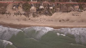 Aerial footage of garden with various vegetation planted on a permaculture concept on sand by the beach. The camera is descending while tilting up.