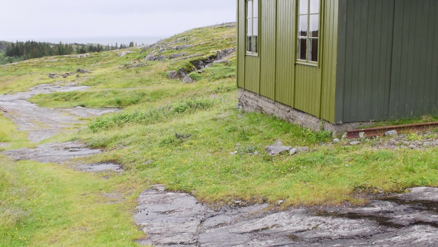 Second World War old German made barracks hut in North Norway Atlantic wall defence line. Green grass growing up and buried slowly old buildings. Tilt up no people footage.