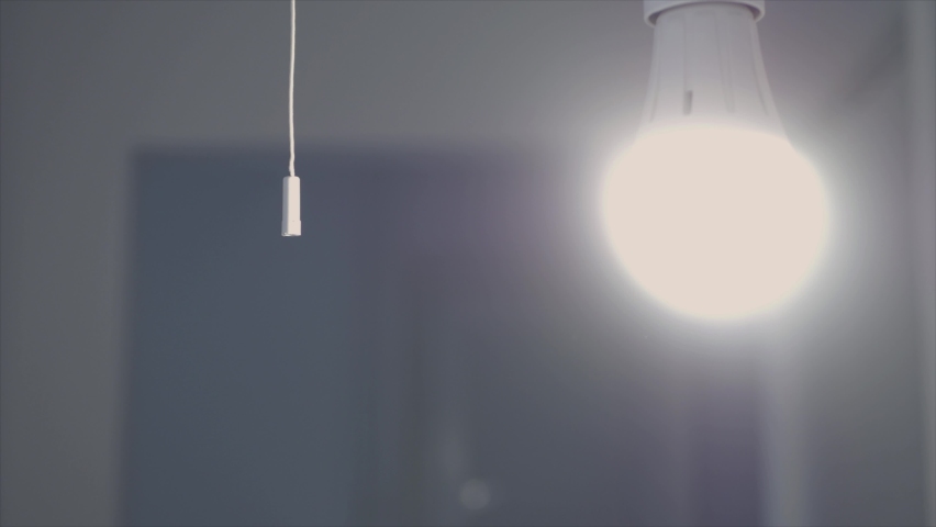Blurred Shooting with a Person Pulls the Switch Cord and Turns Off the Light in a Room. Saving Electricity and Making Economy Concept. Royalty-Free Stock Footage #1096326325